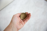 Hollowed-out reverse side of a vintage African bronze pendant showing its handmade texture.