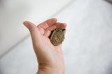 Handmade vintage bronze mask pendant resting in palm, showing collectible scale.