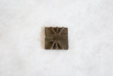 Aged texture and raised geometric motif on vintage African bronze coin.