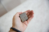 Hand-held vintage African square bronze coin, revealing its unique handmade texture and patina.