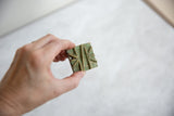 A vintage African bronze coin held to show its geometric pattern and patina.
