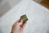 Vintage African bronze coin held to show its size and handmade textural details.
