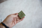 Vintage square African coin held in hand, highlighting its oxidized patina and size.