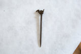 Handmade African bronze bird pin showing its full length and rustic, aged texture.