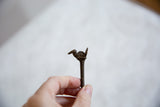 Profile view of the vintage African bronze bird pin held for scale.
