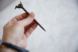 Vintage African bronze bird pin held in hand to demonstrate scale and texture.
