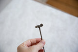 Side profile of the vintage bronze chameleon pin showing its long stem and handmade character.