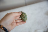 Vintage oxidized African mask pendant held in hand to show its scale and handmade texture.