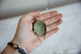 Concave back of the vintage African mask pendant with a textured green patina.
