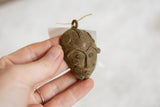 Vintage African bronze mask pendant held to show its scale and textured surface.