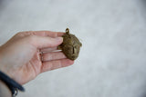 Vintage African bronze mask pendant held in hand to show its scale.