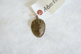 Collectible African bronze mask pendant with handwritten paper tag attached.