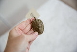 Vintage African bronze mask pendant held in hand, showing handmade details and scale.
