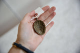 Reverse side of the vintage bronze pendant showing its concave interior and aged patina.