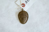 Handmade African bronze mask pendant with textured details and a paper tag.