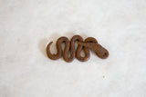 Coiled vintage African iron snake sculpture with rich, textured patina.