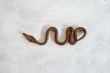 The rough, hand-forged texture of a vintage African iron snake.