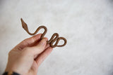 Handmade African iron snake held in hand, showing its compact size and rusted texture.