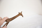Hand holding vintage African bronze giraffe head and neck with aged, textured patina.