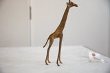 Profile of a vintage bronze alloy giraffe highlighting its aged, textured patina.