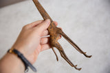 A hand holding a bronze giraffe highlights the figurine's rustic, textured body.