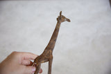 Vintage African bronze alloy giraffe's head and neck, held by a hand, revealing rustic texture.