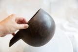 Side view of the antique wooden pitcher held in hand, revealing its dark, aged texture.