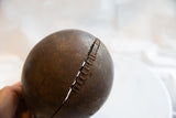 A storied repair with rustic lacing holding together a crack in the antique wooden pitcher.