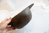 The hand-carved form and aged, pitted texture of a dark wooden pitcher.