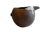 Antique African wooden pitcher with a dark, rustic texture and riveted metal repairs.