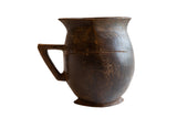 Antique handmade African wooden pitcher, dark brown, with carved texture and aged cracks.