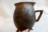 Handmade antique African pitcher's dark wooden surface, showcasing its aged texture and patina.