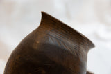 Antique African wooden pitcher with hand-carved linear patterns and aged wood texture.