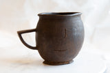 Close-up showing the antique African pitcher's uneven rim and carved wood details.