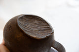 Hand-carved opening with aged texture and deep dark wood of the African pitcher.