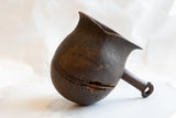 Side profile of an antique African wooden pitcher showing its character-rich cracks and texture.
