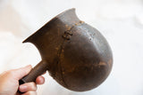 A hand holds the antique wooden pitcher, showing its scale and historic staple repairs.