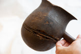 The time-worn texture and a large crack detailing the pitcher's handmade character.