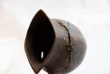Detail of the antique African pitcher's hand-stitched repair and dark, aged wood texture.