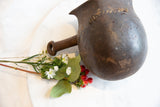 Angled overhead view of an antique African wooden pitcher showing its dark, rustic form.