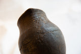 Aged texture and carved lines along the rim of the antique African wooden pitcher.