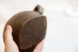 Hand holding antique African wooden pitcher, revealing dark wood with patina and a visible crack.