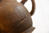 Aged dark brown wood of the antique African pitcher, showing a deep surface crack.