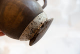 Antique African wooden pitcher base with textured wood, chips, and weathered metal band.