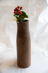 Antique African wooden vase top with rustic texture, red berries, and white flower.
