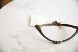 Textured green-brown patina on the curved surface of the antique bronze artifact.