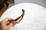 Curved African bronze artifact with aged green patina and etched patterns.