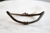 Rich dark patina and etched details on the curved arm of the antique African bronze artifact.