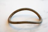 Antique African bronze artifact showing its rustic curved form and textured patina.