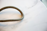 Aged mottled patina on the handmade surface of a curved African bronze artifact.